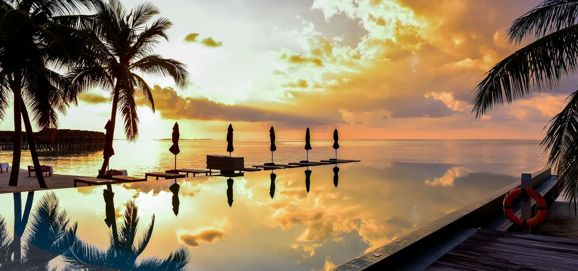 Infinity-Pool mit Palmen bei Sonnenuntergang