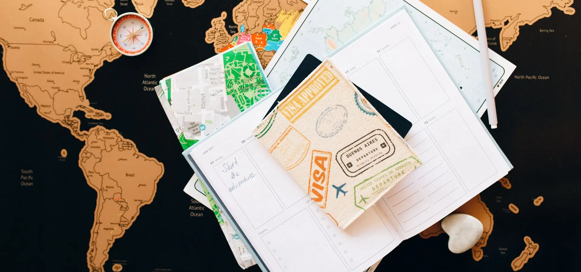 Reisepass, Kompass und Notizbuch auf einer Landkarte